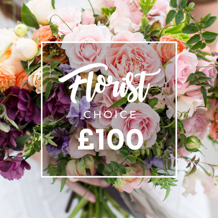 A richly layered, hand-tied bouquet fills the frame with a palette of soft pinks, creamy whites, peaches and a note of deep plum, crafted to feel simultaneously luxurious and freshly picked. Prominent in the arrangement are several full, velvety garden roses in varying shades of pale and blush pink, each rose showing the intricate, ruffled edges and dense petal structure that suggest fragrance and substance. Interspersed among them are light purple and white sweet peas, their slightly translucent petals streaked with subtle veining, and coral-to-peach ranunculus-style blooms whose concentric layers add sculptural depth. Textural contrast comes from clusters of burgundy or plum-toned hellebore-like flowers gathered toward the lower left, which anchor the bouquet and create a sophisticated counterbalance to the softer hues. A profusion of fresh green foliage - from narrow trailing stems to broader leafy greens - is woven throughout, creating a garden-style, organic silhouette and emphasizing a sense of movement. Superimposed centrally over the blooms is a thin white rectangular frame containing an elegant Florist Choice script, CHOICE in smaller uppercase beneath, and a prominent ?100 in bold sans-serif numerals at the base, clearly stating the florist-selected offering and price. The bouquet is held gently at the bottom by a pair of hands, a pale sleeve visible against the soft, out-of-focus background; this human element conveys careful handling and personal service. The overall impression is one of artisan craft and seasonal abundance, suitable for weddings, milestone celebrations or as a considered luxury gift delivered with attention and care.