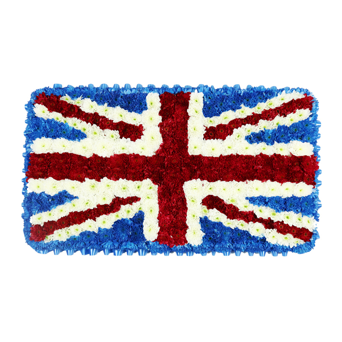 This floral arrangement presents the Union Jack flag as a richly textured, rectangular tribute designed for a funeral or commemorative service. The entire surface is packed with small, uniform flowers that together create a plush, cushion-like effect. Deep blue blooms form the backdrop and outer frame, their consistent tone giving a calm, steady foundation to the design. On this blue field sits the bold red cross of St George, running straight through the centre from top to bottom and side to side, made from densely clustered red flowers whose rounded heads add volume and presence. From each corner, diagonal red bands for St Patrick's Cross reach inward, finely positioned so that every angle matches the traditional flag pattern. Surrounding these red shapes, pure white flowers trace the diagonal and bordering lines of St Andrew's Cross, brightening the composition and providing clear distinction between each colour. The interplay of red, white, and blue is carefully balanced so that no single shade overwhelms the others. Against the plain white background of the photograph, the tribute seems to float, its patriotic colours and meticulous symmetry drawing the eye. As a design you might encounter at a remembrance event or military funeral around Grove Park, perhaps near local churches or community halls tucked behind the station, it conveys both a deep respect for national identity and a tender, human warmth that only fresh flowers can bring. The arrangement feels solemn yet comforting, a quiet, living emblem of British heritage placed at the heart of a moment of farewell.