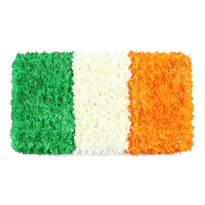 An exquisite rectangular tribute by Grove Park Florist, recreating the Irish Tricolour with meticulous care. The flag comprises three equal vertical bands: left green, center white, right orange, each built from thousands of small petals to form a dense, three-dimensional surface against a pure white backdrop. The left stripe uses emerald green blossoms-likely green carnations or chrysanthemums-packed into a plush carpet with a gentle irregular surface that emphasizes the bouquet's handcrafted character. The central white stripe is a compact cluster of white petals, producing a soft, cloudlike band that visually isolates the color blocks and recalls the island's aspiration for lasting peace. The right stripe mirrors the others in texture and density, comprised of bright orange blooms-likely marigolds or orange chrysanthemums-creating a lively finale. The entire composition maintains strict rectangular proportions, echoing a national flag's exactness while showcasing the florist's skill in layering, colour balance, and petal arrangement. The image reads as both celebratory and solemn, suitable for articles on Irish culture, holiday features, or commemorations, and speaks to Grove Park's pride in supporting local heritage. Available for same-day delivery across Grove Park, this floral artwork blends artistry with accessibility, ensuring its vibrant symbolism reaches customers quickly and intact. It carries a whisper of floral fragrance-the subtle perfume of fresh petals that lingers in the air-making it ideal for schools, libraries, or civic venues preparing for celebrations or remembrance.