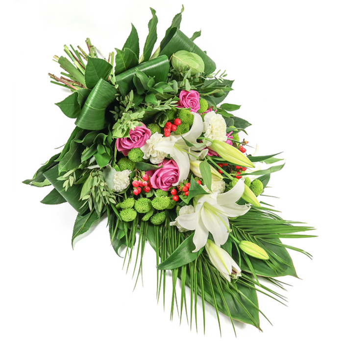 The artistry of Grove Park Florist is on full display in this elongated cascading spray, thoughtfully arranged to extend diagonally across a clear white backdrop-a tribute as dignified as it is heartfelt. Large, pristine white lilies dominate the composition, some fully open to reveal soft yellow stamens, others in tight bud, poised with serene promise. These are interwoven with sumptuous pink and fuchsia roses, from tightly coiled buds to fully open expressions of remembrance and love. Ruffled white spray carnations provide gentle textural contrast and enrich the spray with their softness. Energizing clusters of lime-green button chrysanthemums lend a modern touch, their spherical forms echoing the leafy vitality found near Dukes Meadows. Dotted throughout, bright red hypericum berries offer playful and vivid bursts that enliven the mellow greens. The underlying foliage is lush and diverse, featuring glossy dark green aspidistra leaves, architectural and elegantly folded, alongside lighter feathery greens and cascading palm fronds that amplify the spray's graceful flow. Illuminated in soft morning light, every blossom and leaf becomes a testament to freshness and skilled local craftsmanship. The overall effect is one of composed serenity and quiet reverence, making it a fitting choice for Grove Park funerals, memorials, or any moment requiring a sensitive expression of condolence.