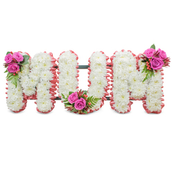 I see this tribute as a florist would: a composed and reverent spelling of MUM, each letter fashioned from compact, pure white chrysanthemums that give a plush, cloud-like surface against a pristine white background. The letters are neatly edged with a soft, ruffled light-pink fabric, which frames the whites with a comforting blush and suggests tenderness in both colour and touch. A dark green support framework is subtly visible between the letters, reminding you this is a standing memorial piece intended to be displayed at a service or graveside. Carefully placed to balance the design are three coordinating posies of rich fuchsia roses, glossy green fern-like foliage and clusters of small reddish-orange hypericum berries - one on the upper left of the first M, one at the inner curve of the U, and the third on the upper right of the second M - which bring life and affectionate colour to the traditional sympathy palette. The effect is quiet and consoling: the chrysanthemums read as purity and remembrance, the pink trim as warmth, and the roses as intimate love. As a local arrangement prepared for families across Grove Park, Lee and nearby Downham, this style is often chosen for a mother's service; Grove Park Florist can craft and deliver this tribute for funerals, wakes or graveside gatherings with the care local customers expect.