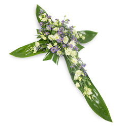 Viewed from a gentle overhead perspective against stark white, this floral cross reads as both architectural and tender: broad tropical leaves-glossy, veined Ti-like foliage-form the defined arms and centre spine of the cross, their rich green acting as a calm foundation. Resting atop and concentrated at the crossing are clusters of soft, ruffled lisianthus in ivory and pale cream, their many-layered petals creating an impression of quiet luxury. Nestled among them are compact white daisylike chrysanthemums or miniature spray roses that add points of light, and delicate sprays of lavender-hued limonium or asters that introduce a soft, cooling contrast. Slender sprigs of fine green filler are threaded through the blooms, breaking the silhouette gently and giving the composition a lived-in, natural texture. Studio lighting bathes the piece evenly, heightening the contrast between the smooth, waxy leaves and the feathery softness of the flowers while keeping the mood serene rather than dramatic. The scent would be subtle-green and fresh-suiting moments of mourning and remembrance. This arrangement is suited to church services, memorials, and wakes across Grove Park and neighbouring streets near the station, made to communicate compassion and everlasting peace in a restrained, tasteful manner.