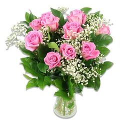 Set against a pure, uncluttered white background, a vase of pink roses and baby's breath captures the kind of understated elegance often favoured in Grove Park homes. The bouquet, arranged in a clear glass vase, features roughly ten to twelve roses in varying stages of bloom, all in harmonious shades of soft, blush pink through to a slightly deeper, candy-like tone near the centres. Some roses are open wide, revealing intricate, velvety spirals of petals that curl back gracefully, while others still hold their shape more tightly, like buds on the verge of unfolding, mirroring the sense of anticipation when a new baby joins the family. Woven through this rosy dome are slender stems of white baby's breath, each bearing clusters of tiny, star-shaped flowers that form an airy, cloud-like layer between the larger blooms. Rich, dark green foliage surrounds the flowers, the glossy leaves providing visual weight and contrast, making the pastel shades stand out clearly. The transparent vase reveals the neat bundle of green stems resting in clear water, a subtle reminder of the bouquet's freshness and thoughtful conditioning, as you might expect from a local Grove Park florist delivering along Burlington Lane or near the quiet streets by the Thames. The lighting is soft but bright, enhancing the natural sheen of the petals and the delicate, feathery quality of the Gypsophila without overwhelming them. Altogether, the arrangement feels calm, tender, and welcoming, well suited to congratulating new parents, decorating a baby shower table, or adding a gentle touch of joy to a nursery or family room in the Grove Park area.