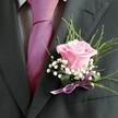 A sense of poetic celebration fills this buttonhole arrangement, lovingly assembled by florists along Grove Park's winding lanes. At its heart, a blush-pink rose opens softly in layers, petals velvety and fresh-as if capturing the gentle play of light at nearby Chiswick House. The rose's fragrance lingers delicately, a quiet invitation for new beginnings. Surrounding it, airy tufts of baby's breath evoke the softness of morning clouds, wrapping the central bloom in a halo of gentle white. Graceful arcs of green foliage provide uplifting structure, bringing a note of wild beauty reminiscent of Grove Park's tree-lined walks. Resting on the lapel of a charcoal suit and paired with a lilac-pink tie, the boutonniere radiates with subtle charm, every element bound by a matching satin ribbon. For wedding celebrations or milestone gatherings in Grove Park, this hand-tied piece becomes more than a floral accent-it's a promise of joy, crafted with skill and a deep appreciation for the nuances that make each moment unforgettable.