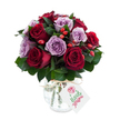 A richly hued, hand-arranged bouquet of fully opened roses, where deep crimson and velvety burgundy blooms sit cheek-by-jowl with soft lavender and dusty mauve roses, forming a dense, rounded dome of petals. The roses show delicate unfurling edges and a satiny sheen that catches the light, while clusters of small, bright red-orange rose hips nestle between the blossoms, offering a lively, textured contrast like berries picked from a hedgerow after rain. Dark green foliage - the glossy, slightly leathery leaves of Ruscus or Salal - frames and fills the bouquet, its cool tones deepening the warmth of the roses and creating a sense of depth and fullness. The flowers are gathered in an antique-effect mercury glass vase: rounded at the base and tapering toward the neck, its silvered, mottled surface reflecting soft highlights and giving the arrangement a quietly elegant, vintage character. A simple piece of natural raffia or twine is tied around the vase's neck and from it hangs a small, rectangular white gift tag with a delicate floral sketch and handwritten-style message in green and pink tones, suggesting a personal note tucked in for a loved one. Set against a brilliant white background, the colours read vividly and the reflective vase shimmers without distraction. The overall impression is romantic and thoughtfully composed - a bouquet that radiates warmth and refined charm, ideal for anniversaries, heartfelt thank-yous, or simply brightening a home in Grove Park with fresh, artisan floristry.