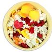 From a top-down angle, the photograph reveals a circular, light yellow bowl filled completely with a carefully gathered selection of rose and hydrangea petals, creating a soft, tactile tribute ideal for a Grove Park funeral setting. The bowl's pale cream-yellow glaze has a gentle warmth, almost like filtered afternoon light falling across a dining table in a Grove Park home. Within it, rose petals lie in generous layers, curving and folding in rich crimson red, bright sunshine yellow, and mellow peach-apricot. Each petal has a velvety thickness that catches the light along its edges, giving the impression of depth despite the shallow bowl. Threaded among these bold colours are clusters of small, crisp white hydrangea florets, their fine, tissue-like petals adding a cool contrast and lacy texture. The mix is loose and organic rather than rigid, as though the petals have just been freshly scattered by hand, rising in a gentle mound that reaches the rim. The interplay of colour suggests both the weight of grief and the warmth of remembrance-deep reds for enduring love, yellow and peach for shared laughter and kindness, white for peace and rest. It's easy to imagine this bowl set on a memory table at a local service, perhaps near Grove Park station or by one of the area's quiet churches, where family and friends might pause to reflect, their eyes resting on the calming pattern of petals. The arrangement feels intimate and thoughtfully composed, a small, beautiful gesture that softens the space around farewell and offers comfort through simple, natural beauty.