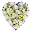A softly glowing heart-shaped floral tribute is displayed against a pure white backdrop, its harmonious blend of white, cream, and muted green tones creating a feeling of calm remembrance. Centrally placed is a single creamy white rose, its gently spiralling petals forming the emotional anchor of the piece, like the cherished memory of a loved one. From this centre, layers of white carnations swell outward, their frilled petals overlapping to give the heart a plush, cloud-like texture that feels soothing and protective. Interlaced between the carnations are elegant white spider chrysanthemums and daisy-like blooms, their narrow, spiky petals and pale green or subtle yellow centres adding movement and delicate detailing without disturbing the serenity of the design. Here and there, creamy rosebuds and lisianthus buds are nestled thoughtfully, some still closed, suggesting love and stories that continue to unfold. Sprigs of blue-green eucalyptus thread gently through the flowers, providing contrast, depth, and a suggestion of fresh, clean fragrance, like a breeze drifting through the trees around Grove Park and nearby Chiswick. Defining the outline of the heart, a rich purple ribbon is carefully pleated and ruffled along every curve, forming a dignified border that enhances the romantic shape and solemn purpose of the tribute. The lighting is soft yet clear, highlighting the freshness of each bloom as if the tribute has just been prepared in a Grove Park Florist studio for same-day delivery to a local funeral, memorial service, or chapel of rest. The overall impression is of a thoughtfully crafted sympathy heart, expressing peace, honour, and heartfelt condolences for families in and around Grove Park.