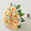 Brought to life for the special celebrations of Grove Park, this bouquet is an exquisite testament to gentle romance and thoughtful design. Twelve peach and apricot roses lift their blossoms proudly from the centre, each petal swirling in delicate shades from blush to amber, emanating warmth much like the sunlight filtering through the neighbourhood's canopy. Misty clusters of baby's breath surround the roses, adding a soft, ethereal contrast that feels both classic and modern, reminiscent of freshly laundered linens hanging in local gardens. Polished green leaves line the arrangement, providing structure and an uplifting burst of colour. The hand-gathered stems are tightly wrapped with peach satin ribbon, its surface dotted with small pearls that catch the light gracefully-perfect in hand and brimming with sentiment. Set upon a pale, tactile background, the bouquet glows quietly with all the elegance and hope of the moment, making it an ideal flourish for weddings, engagement parties, or any cherished gathering in Grove Park.