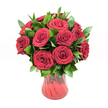 A lush, romantic bouquet of roughly twelve to fifteen deep crimson red roses is gathered in a translucent red glass vase, photographed against a pure white studio background so every detail stands out. Each rose is fully open yet still full of life, with velvety petals curling into perfect spirals at the centre and gently softening at the edges, creating layers of rich texture that seem almost touchable. The blooms are grouped in a classic rounded shape, forming a luxurious dome of ruby colour that immediately suggests passion, devotion, and timeless romance. Threaded between the roses is an abundance of dark, glossy green foliage, likely ruscus or similar greenery, adding depth, contrast, and a sense of natural movement to the design; the leaves arc out from the blooms, framing them with a lively, verdant halo. The red vase has a gently curving silhouette that narrows towards the base and flares delicately at the neck, with a subtle ribbed or swirled texture in the glass that catches the light and adds quiet sophistication. Its translucency lets hints of the rose stems and deeper red tones show through, unifying the whole arrangement. The crisp white background and even lighting highlight the intensity of the red and the freshness of the greens, giving the impression of a bouquet freshly arranged in a Grove Park florist's workshop, ready to be delivered for a Valentine's surprise, a special anniversary, or a heartfelt declaration of love anywhere around Grove Park station or the tree-lined streets nearby. The overall mood is intimate, elegant, and confidently romantic, like a still moment captured just before the bouquet is handed to someone cherished.