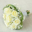 A composed, classic bridal bouquet photographed at a gentle diagonal on light beige linen: seven prominent creamy-white roses take centre stage, their soft petals unfurling in varied stages of bloom to create depth and a feeling of fullness. Around and between these roses, delicate clouds of white baby's breath (Gypsophila) nestle closely, lending an ethereal, weightless texture that softens the silhouette. Smooth, ribbon-like loops of green bear grass are woven around the bouquet's edge, giving a subtle graphic frame that contrasts the round roses with vertical movement and a hint of meadow freshness. The stems are tightly bound into a streamlined handle and finished in silvery-white satin ribbon, where neat rows of tiny pearl beads are sewn on as an elegant, vintage-inspired trim. Placed against a neutral woven fabric, the bouquet's creamy tones and green accents are accentuated by soft, even light that clarifies petal detail and the satin sheen of the wrap. As a Grove Park Florist I craft these with the same care seen here - they are ideal for local venues from the corner churches to small halls near Grove Park station and for customers requesting same-day freshness across the neighbourhood. The overall effect is refined and calm: romantic without fuss, classic without being old-fashioned, a design that suggests purity, gentle celebration, and the quiet confidence of conscientious floristry.