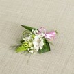 A delicately handcrafted boutonniere rests on a softly textured, light beige linen-style cloth, the neutral backdrop allowing every petal and leaf to stand out with quiet clarity. At the heart of this compact design sits a single white alstroemeria bloom, its broad petals gently ruffled at the edges and brushed with fine reddish-brown speckles near the throat, like careful strokes of watercolour. The flower is fully open, revealing pale stamens that add to its sense of freshness, as if it has just been prepared in a Grove Park workshop minutes before a ceremony. To the left, a tapered cluster of vivid lime-green buds, tightly packed into a conical spike, offers a striking contrast in both colour and texture, its scale-like pattern catching the even, natural light. Around these focal elements, tiny white clouds of baby's breath drift through the composition, their airy sprays softening the overall silhouette and suggesting a light, whispery movement. The foliage underneath and behind the blooms is thoughtfully layered: broad, dark green, pointed leaves provide structure and depth, while bright, grass-like fronds weave in and out, adding a sense of flow that echoes the gentle curves of local tree branches along Grove Park's quiet residential streets. At the right-hand side, a glossy satin ribbon in cheerful pink is tied into a small, neat bow, neatly gathering the stems and introducing a note of playful romance. The lighting is even and calm, with no harsh shadows, highlighting the fresh textures and subtle colour shifts. This refined floral accessory feels perfect for a wedding, prom, or anniversary celebration in Grove Park, designed to sit gracefully on a lapel or wrist and to accompany intimate photographs and meaningful vows.