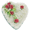 A tender, heart-shaped memorial wreath made entirely from a dense, cloud-like bed of pristine white chrysanthemums rests against a clean white background, its soft texture suggesting comfort and quiet peace. Each tiny chrysanthemum is tightly placed to form a seamless, cushiony surface that reads as purity and remembrance; the overall halo of white has a powder-soft sheen under gentle overhead light, with faint, natural shadows that reveal the subtle undulations of the floral cushion. From the upper left a composed spray of deep crimson roses sweeps across the white field: three richly hued blooms clustered together amid glossy broad leaves and airy, fern-like fronds, their petals open and velvety. Two additional solitary red roses punctuate the composition - one near the right-hand curve and another at the lower point - each framed by minimal green accents and a few slender, arching blades of grass that lend a flowing, human touch. A narrow emerald-green satin ribbon trims the heart's entire perimeter, its cool sheen providing a precise edge and a discreet, dignified frame. The scent is understated - a gentle rose perfume layered over the faint, earthy sweetness of chrysanthemum - and the overall mood is reverent and composed. This is the sort of traditional sympathy piece you might see at a Grove Park funeral service or left gently at a graveside near Chinbrook Meadows, made to convey enduring love, deep respect, and consolation after loss. Presented with the care of an experienced local florist, it reads as both a visual tribute and a tactile embrace for grieving families.