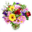 In this photograph, a generously proportioned bouquet of mixed seasonal flowers sits in a clear glass vase against a crisp white background, allowing every hue and texture to be imagined in detail. The bouquet forms a rounded, slightly domed silhouette, filled so fully that the flowers gently press together, conveying abundance and care. Deep red roses take centre stage, their velvety petals coiling outward in rich layers, giving the design a romantic, heartfelt core. Just off-centre, two bright yellow gerbera daisies with dark brown-orange centres add a bold burst of sunshine, their flat, open faces offering a playful contrast to the more traditional roses. Encircling these focal flowers, clusters of soft pink and lilac-tinged daisies or chrysanthemums fan outwards, made up of many slim, delicate petals and tiny yellow centres that add both texture and a calm, pastel glow. Threaded gracefully through the arrangement are stems of purple and lavender lisianthus, their bell-shaped blossoms and slightly wavy petals adding a note of cool elegance and a gentle vertical lift. Bright red hypericum berries, smooth and round, appear here and there among the petals, bringing an unexpected contemporary touch and a pleasing change in form. A mix of dark, glossy leaves and lighter, more delicate greenery frames the blooms and spills softly over the vase edge, enhancing the bouquet's freshness and giving it a natural, garden-inspired feel. Through the glass, neatly trimmed stems are visible in clear water, a subtle sign of quality and care, typical of Grove Park Florist. The overall mood is warm and celebratory, perfectly suited to brighten a home near Grove Park station, accompany a relaxed gathering by the river, or simply send a colourful message of kindness across the local community.