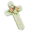 A refined floral cross, designed as a sympathy tribute, fills the image against a simple, bright white background that gives it a sense of stillness and clarity. The cross's structure is entirely clad in white chrysanthemums, specifically small button blooms arranged so closely together that they create a thick, uniform surface. Their compact petals form a soft, velvety carpet of white, evoking purity, reverence, and the quiet calm often sought at funerals and memorials. At the centre, where the arms of the cross meet the vertical beam, a cluster of roses introduces a gentle focal point. These roses are fully open and layered, glowing in pastel tones of blush pink, creamy white, and soft peach, their rounded petals suggesting tenderness and enduring affection. Surrounding them, slender green fern fronds and fine sprigs of pale lavender or light purple filler flowers weave in and out, adding both textural contrast and a subtle wash of colour that softens the overall design. Along the outer edge of the cross, a narrow lime green ribbon creates a delicate border, just visible beneath the chrysanthemums, giving the tribute a crisp outline and a touch of fresh, modern character. The arrangement feels like something chosen for a thoughtful farewell at a Grove Park church or a quiet service near Chiswick and the riverside, where families gather to honour a loved one's faith and life. With its careful craftsmanship and balanced palette, this floral cross offers a calm, dignified presence and a heartfelt expression of condolence.