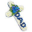 Against a clean, bright white backdrop, a large floral cross is shown in full view, its simple elegance and emotional weight conveyed through colour and texture. The entire cross is densely covered with white spray chrysanthemums, their small, multi-petalled blooms forming a uniform, cushion-like surface that softens the solid outline. Bordering this field of white is a royal blue satin ribbon, carefully arranged to trace every edge of the cross with a crisp, gleaming frame. At the centre where the arms meet, a vibrant spray of royal blue flowers provides a striking focal point: layered, ruffled blue carnations combine with slender blue stems reminiscent of delphinium, creating a dynamic cluster that rises gently from the white base. Around these, dark green fern fronds and polished leaves arch outward, adding depth and a natural, garden-like touch. Along the vertical stem, the word DAD is spelled out using the same royal blue ribbon, each letter carefully formed and secured into the chrysanthemum surface so that the tribute feels both formal and tenderly personal. The lighting is soft and even, leaving only the lightest shadow beneath the cross, which subtly hints at its thickness and meticulous construction. This arrangement exudes calm, reverence, and enduring affection, an appropriate floral tribute for honouring a father at a funeral or memorial in Grove Park. Its pure whites and deep blues invite quiet reflection, much like pausing on a bench in Grove Park itself or along nearby residential streets to remember someone who meant the world.