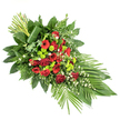 A beautifully composed funeral spray stretches across a plain white background, its elongated form guiding the viewer's eye from a lush, flower-rich centre outward to more delicate points of greenery. The shape recalls a classic casket spray or formal memorial tribute, with a gentle, tapering flow that feels calm and intentional. Deep red hues dominate the floral story: velvety roses sit at the heart of the design, some blooms fully open, revealing soft, layered petals, while others remain as dignified buds, capturing the dual sense of loss and lingering presence. Alongside them, red gerbera daisies with dark eyes and rounded clusters of ruffled red carnations add variety of form and richness of texture, deepening the emotional tone. In contrast, lime-green chrysanthemum button pompons are threaded through the arrangement, their small, spherical blooms providing bright, almost luminous accents that lift the entire piece and add a contemporary feel. Delicate sprinkles of tiny white filler flowers, likely gypsophila or small daisies, soften the transitions between colours, giving the spray a lighter, more breathable appearance. A strong base of fresh foliage supports the flowers: broad, glossy dark green leaves, airy leatherleaf fern, and mixed greenery create a full, layered backdrop that frames the central blooms. At the lower right, long, slender leaves fan outward, emphasising the sense of motion and direction, while at the upper left, a vertical bundle of green stems, wrapped neatly with a single folded leaf, contributes a structured, modern note. The overall impression is one of dignity and serenity, making this arrangement a fitting tribute for a funeral or memorial service in Grove Park, whether displayed in a local church, at a small chapel, or delivered to a family home as a heartfelt gesture of condolence.