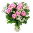 Against a pure white background, a clear glass vase brims with pink roses and white baby's breath, capturing a soft, joyful mood that feels perfectly at home in Grove Park's peaceful, tree-lined neighbourhoods. The bouquet includes approximately ten to twelve roses in a range of blush and mid-tone pinks, their petals layered in smooth, velvety spirals that open outwards from centres touched with slightly deeper colour. Some blooms are open and expansive, displaying their full, ruffled beauty, while others rest in more modest, half-open forms, suggesting freshness and the promise of new life-an ideal echo of the emotion surrounding a baby's arrival. Woven among these larger flowers, delicate sprays of baby's breath (Gypsophila) scatter clusters of tiny white blossoms, creating a misty, cloud-like effect that softens the structure of the bouquet and adds a sense of lightness. Around the base and between the blooms, dark green rose leaves and foliage provide a rich, glossy backdrop that enhances the soft pink and white tones. The vase itself is simple and transparent, revealing the gathered green stems and the clear water that nourishes them, much like a freshly prepared arrangement ready to be delivered from Grove Park Florist to a family home near Strand on the Green or along the quiet residential roads. Gentle, even lighting allows each petal and tiny Gypsophila flower to be imagined in detail, from the smooth curves of the roses to the fine, branching stems of the filler. The overall atmosphere is tender, peaceful, and quietly festive, ideal for baby showers, first visits to the hospital, or welcoming a newborn into a cosy Grove Park home.