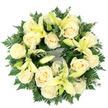 Seen from above against a clean white backdrop, this circular sympathy wreath presents a calm, understated beauty: creamy ivory roses and soft pale-yellow lilies woven into a dense ring of deep green foliage. The roses-around a dozen to fifteen large blooms-sit with their classic, tightly spiralled petals, giving a quiet, luminous ivory surface that catches a soft, cool light. Between them, trumpet-shaped lilies in a gentle lemon tone open in varying stages; some reveal their slender stamens and gracefully flared petals, others remain in bud, lending a sense of gentle pause and future unfolding. The base is a tapestry of rich greenery-feathery fern fronds that edge the wreath with delicate texture and rounded, silvery-green sprigs of eucalyptus that add contrast and depth. The greenery frames and cradles the blooms, creating a lush, supportive cradle that accentuates the flowers' pale tones. There is a subtle fragrance in the imagined air: a powdery sweetness from the roses and a clean, green hint from the lilies that together feel respectful and calming. The perfect circular form reads as an emblem of continuity, an unbroken gesture of remembrance and consolation suitable for a funeral service, graveside tribute, or a memorial gathering. Crafted with careful balance and dense, precise placement, the wreath conveys purity, peace, and gentle reassurance-an elegant, comforting tribute that speaks with quiet dignity and soft light.